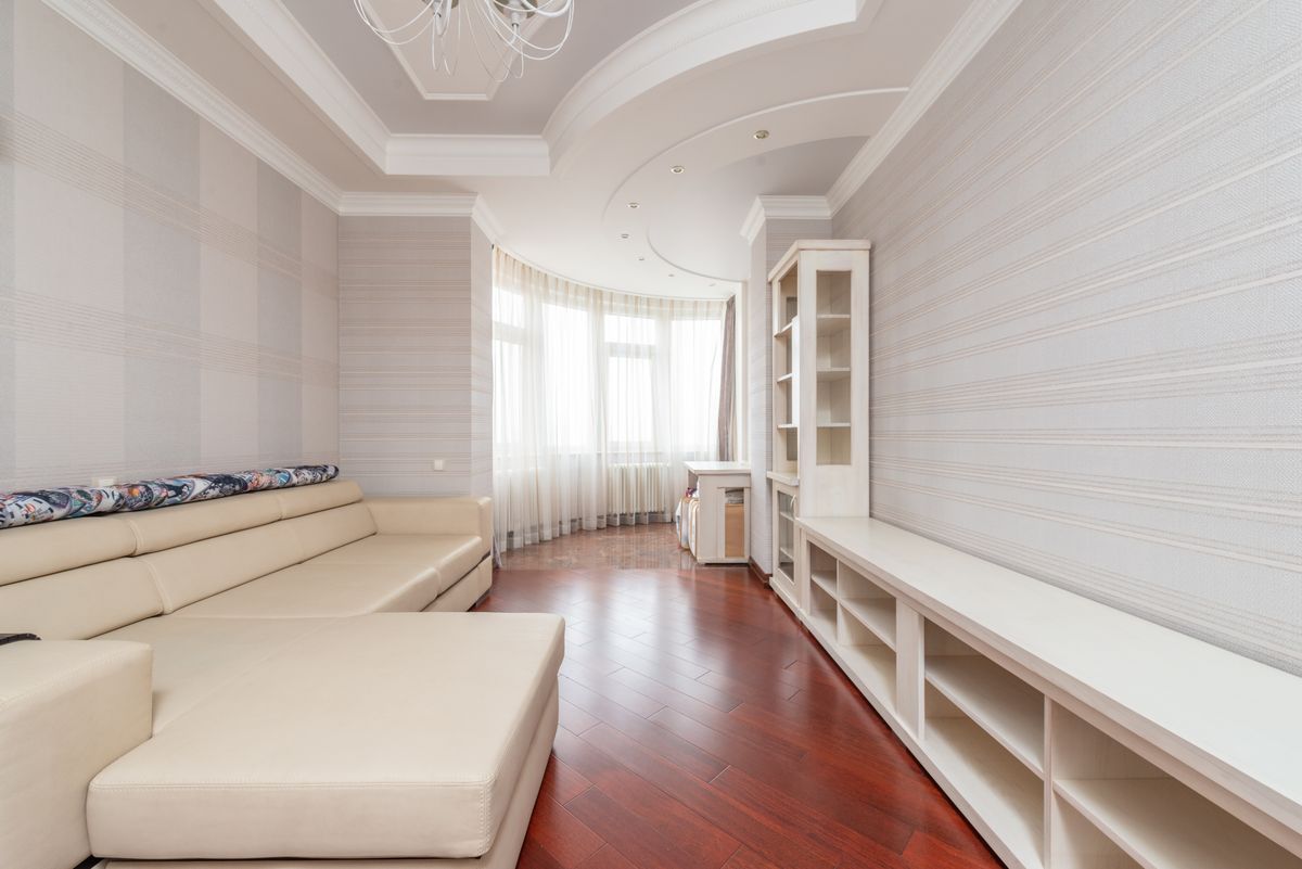 Renovated living room with a smooth multi-level white ceiling, recessed lights, and a curtained bay window